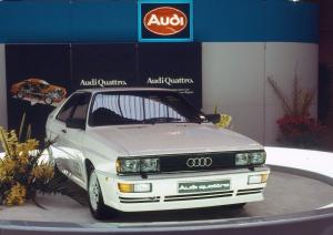 1980: five-cylinder gasoline engine with turbocharger and intercooler: In 1980 at the Geneva Motor Show, Audi unveils the Audi quattro (B2), known as the â€œUr-quattroâ€ from the mid-1990s. It uses the powerplant from the Audi 200 5T (C2), but features an intercooler. As a result, the turbocharged engine achieves a higher output of 147 kW (200 hp) at 5,500 revolutions per minute and 285 newton meters (210.21 lb-ft) of torque at 3,500 rpm. The body of the Audi quattro is based on the Audi Coupe (B2), which in turn is based on the Audi 80. Flared fenders, bulkier bumpers and sills as well as a larger rear spoiler distinguish the Audi quattro from the Coupe.